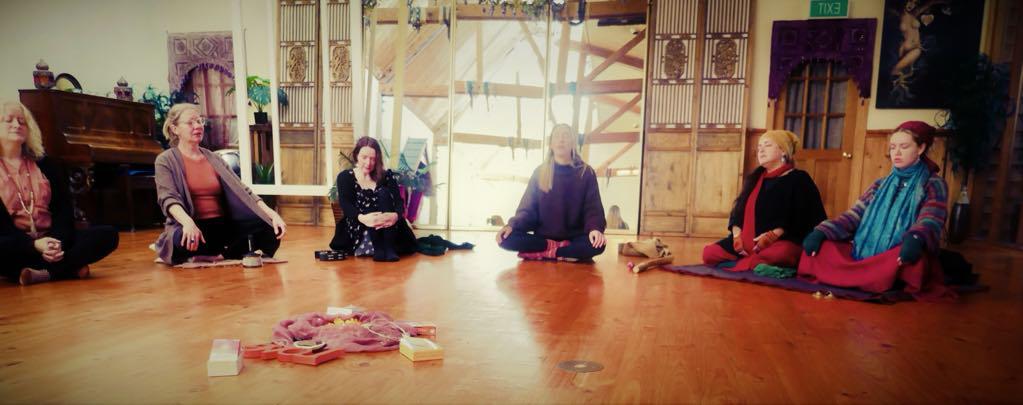 Women sitting in a singing circle in the monastery hall